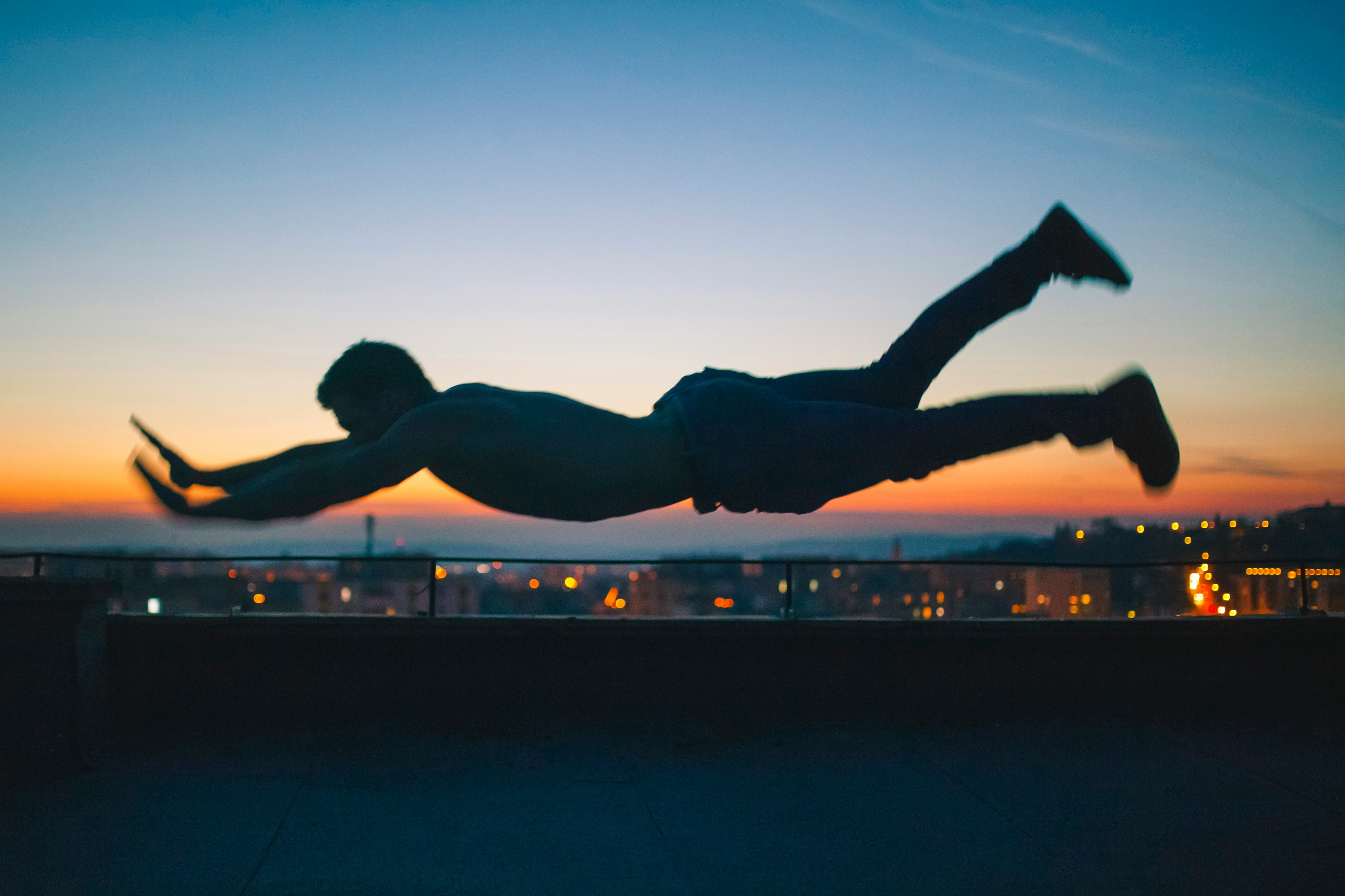 gray scale photo of man falling during golden hour